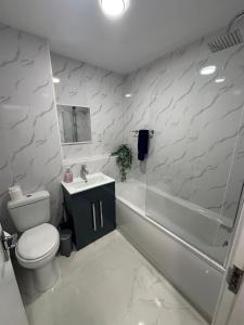 a bathroom with a toilet and a tub and a sink at Spacious 1bed Apartment Close To Town in Ifield