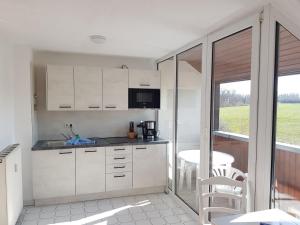 a kitchen with white cabinets and a table and chairs at Fewo 18 im Strandhaus Lobbe mit Balkon in Lobbe