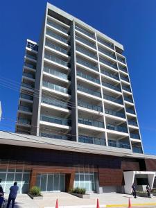 a tall building with people standing in front of it at Studio na Av Esmeraldas com garagem in Marília