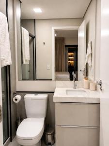 a white bathroom with a toilet and a sink at Studio na Av Esmeraldas com garagem in Marília +30 photos