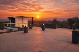 a sunset on the roof of a building with lights at Casa Oceanus - Pool View Room - Ganpatipule in Nevra