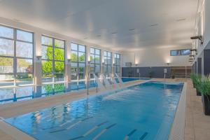 a large swimming pool with chairs in a building at AquaMed Hotel Harkány in Harkány