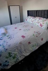 a bed with a white comforter with flowers on it at Stratford Terrace in Beeston +5 photos