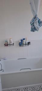 a white bathroom with a bathtub and a shelf of items at Stratford Terrace in Beeston