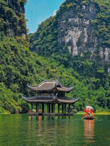 a pagoda in the middle of a lake in front of a mountain at Tam Coc Cozy Hotel in Vũ Lâm