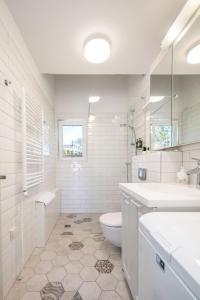 a white bathroom with a toilet and a sink at Preilos Perliukas in Preila +55 photos