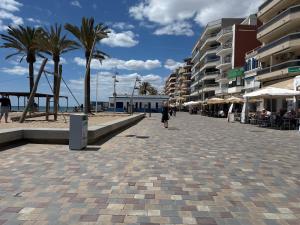 a woman walking down a sidewalk next to a beach at Suitte Catalunya in Calafell