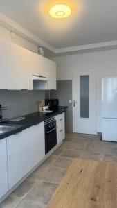 a kitchen with white cabinets and a black stove at Pau Elégance - 4 Personnes - Pau Hyper Centre - Clemenceau in Pau