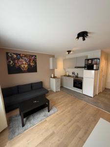 a living room with a black couch and a kitchen at S22 Living in Weingarten (Karlsruhe)