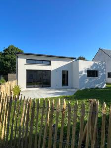 a white house behind a fence at Le Cottage Bigouden in Combrit