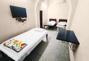 a room with two beds and a flat screen tv at Lodha Heritage in Ajmer