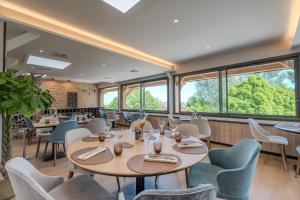 a restaurant with tables and chairs and windows at LE VAL MORET Hôtel Restaurant et Spa in Magnant