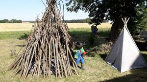 a young child standing in front of a thatch hut at Ferienwohnungen auf dem Lande in Kittendorf