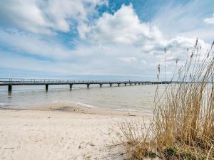 a pier over the water with a sandy beach at Ferienwohnung Kranich - Dranske in Dranske