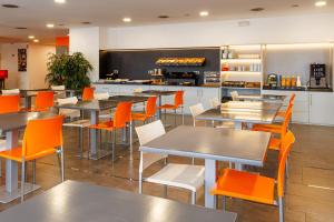 a restaurant with tables and chairs and a kitchen at Hotel H2 Avila in Ávila