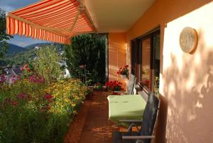a patio with an umbrella and a table and flowers at Ferienwohnung Abendsonne in Neuhof