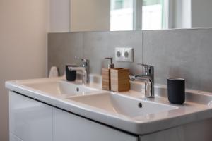 a white bathroom with two sinks and a mirror at App Osiria in Kühlungsborn
