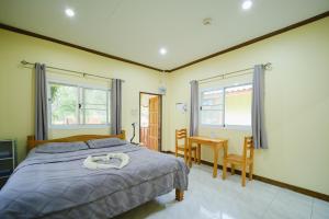 a bedroom with a bed and a table and chairs at Baanrimklong bungalow in Ko Chang