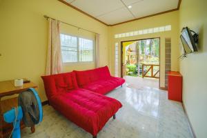 a red couch in a living room with a tv at Baanrimklong bungalow in Ko Chang