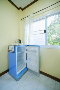 a kitchen with an open refrigerator and a window at Baanrimklong bungalow in Ko Chang