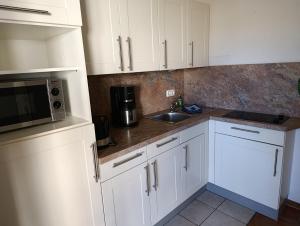 a kitchen with white cabinets and a sink and a microwave at Hermannstr 14-Whg 10 in Kühlungsborn
