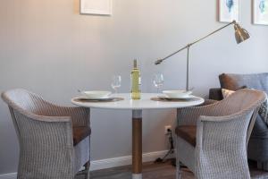a white table with two glasses and a bottle of wine at App Flamingo in Kühlungsborn