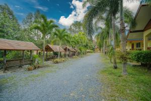 a dirt road with palm trees and buildings at Baanrimklong bungalow in Ko Chang