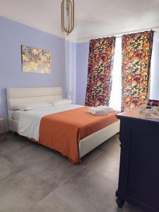 a bedroom with a bed with orange blanket and curtains at Le stanze del Corso in Monreale