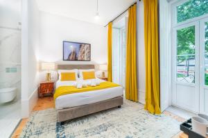a bedroom with a bed with yellow curtains and a bathroom at A&S Suítes Coimbra in Coimbra +69 photos