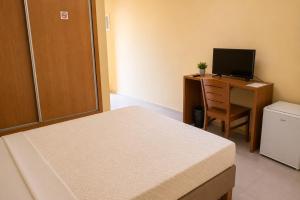a bedroom with a bed and a desk with a television at Viana Hotel in Luanda +1 photo