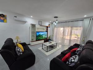 a living room with two couches and a flat screen tv at Mel's Apartment in Ndola