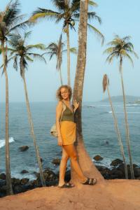 a woman standing next to palm trees on the beach at Mira Mirissa in Mirissa