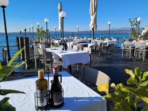 a restaurant with white tables and bottles of wine at Hotel Pace in Sirmione