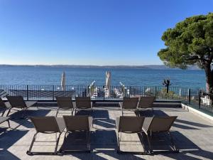 a row of chairs on a patio next to the water at Hotel Pace in Sirmione