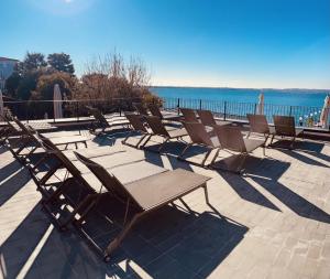 a row of chairs sitting on a patio near the water at Hotel Pace in Sirmione
