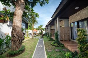 a house with a walkway next to a tree at Ulu Apsura Villas in Uluwatu +8 photos