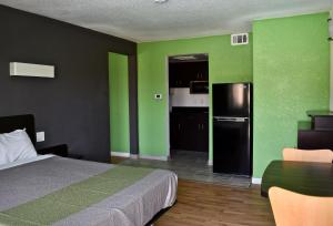 a room with a bed and a kitchen with green walls at Studio 6-Barstow, CA in Barstow