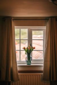 a vase of flowers sitting on a window sill at Boot & Shoe in Flintham