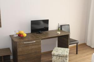 a room with a desk with a television and a chair at Sea & Hill Guest Houses хотелски тип in Lozenets