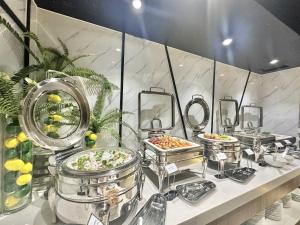 a buffet line with several dishes of food and mirrors at Queen Ann Hotel in Ho Chi Minh City