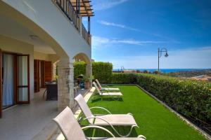 a patio with chairs and a green lawn at Ground floor Apartment Anthos with Beautiful Sea Views on Aphrodite Hills Resort in Kouklia