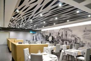 a dining room with white tables and white chairs at Hotel & Spa Ciudad de Binéfar in Binéfar