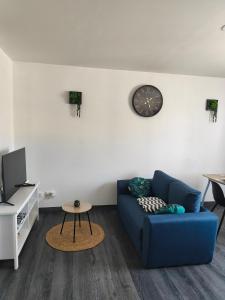 a living room with a blue couch and a clock on the wall at point baie studio 1 in Abbeville