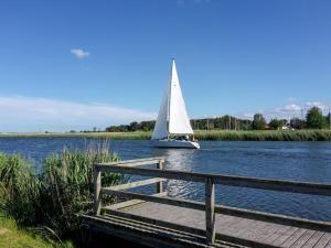 a sailboat on the water next to a wooden dock at Luzie's Hus in Freest +21 photos