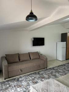 a living room with a brown couch and a refrigerator at RADUGA West in Koshkolʼ +1 photo
