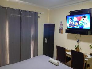 a room with a bed and a television and a table at Capim de Ouro Flats Mobiliados in Palmas