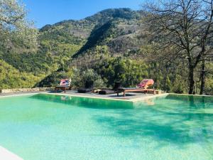 a pool of water with two chairs and chairs in front of a mountain at Il wokini in Castel Vittorio
