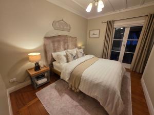 a bedroom with a bed and a lamp and a window at Kingfisher Lodge Waterfront Retreat in Tairua