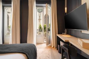 a bedroom with a bed and a desk with a television at Hotel de Nell in Paris