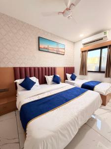 a bedroom with two beds with blue and white sheets at HOTEL ROSE PRIMe in Anand +7 photos